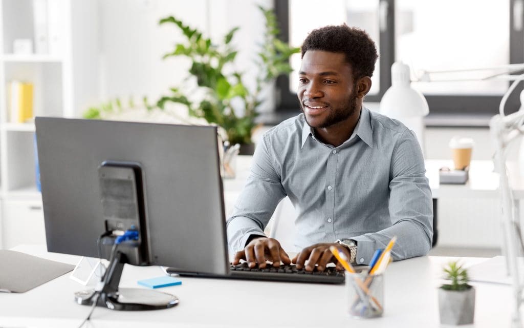 Side view of a man smiling at computer monitor
